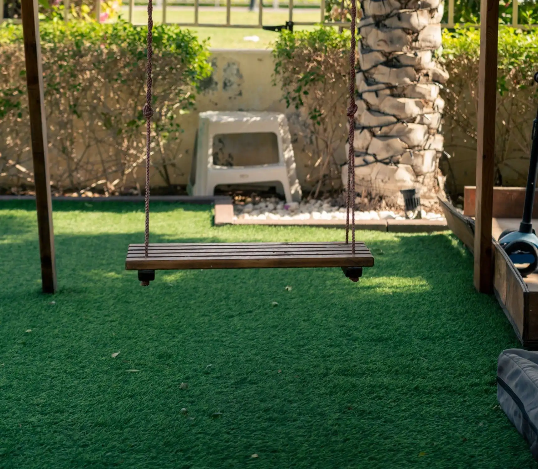 Wooden swing over a small artificial turf play area